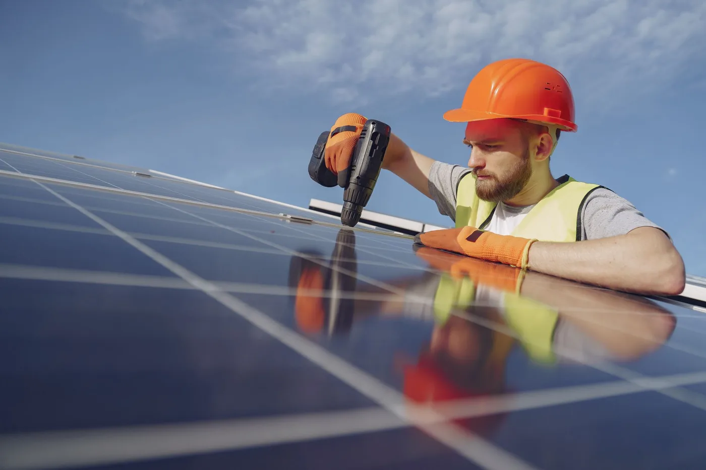Elektrikář instaluje fotovoltaický panel na střeše